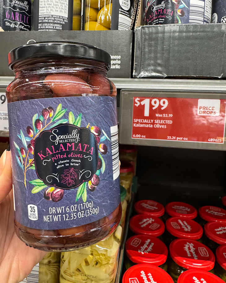Someone holding jar of Kalamata olives from Trader Joe's