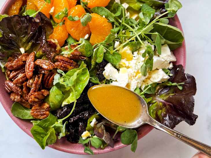 Someone spooning Joanna Gaines Red Wine Vinaigrette over a salad