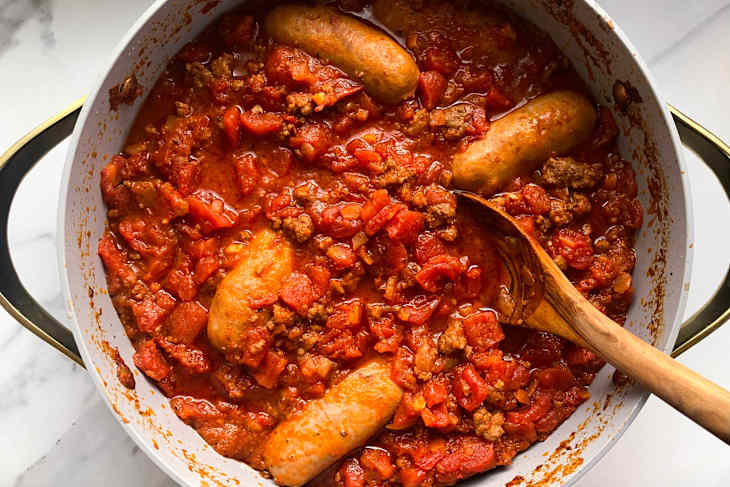 Pot of spaghetti sauce with sausage and ground meat.
