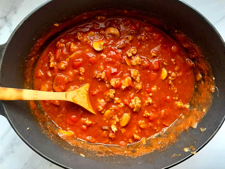 Spaghetti sauce cooking on stove with wooden spoon