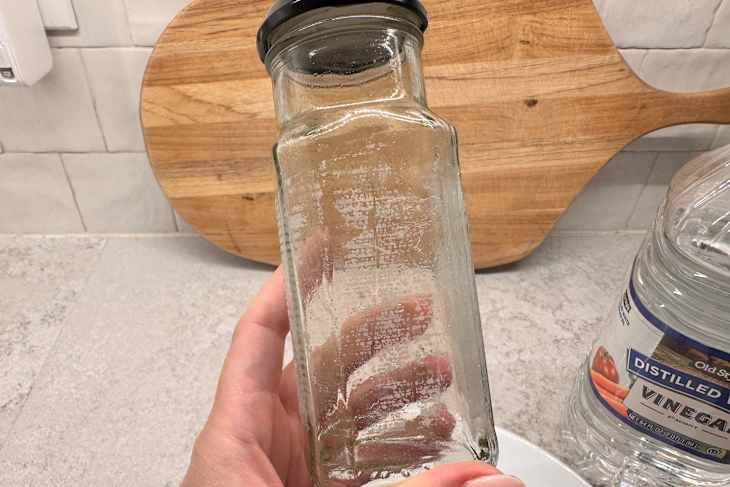 Someone holding spice jar with sticker removed before fulling cleaning.