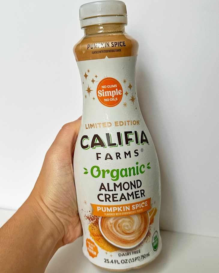 Limited edition Califia Farms Organic Almond Creamer in Pumpkin Spice flavor, held in a hand against a white background.