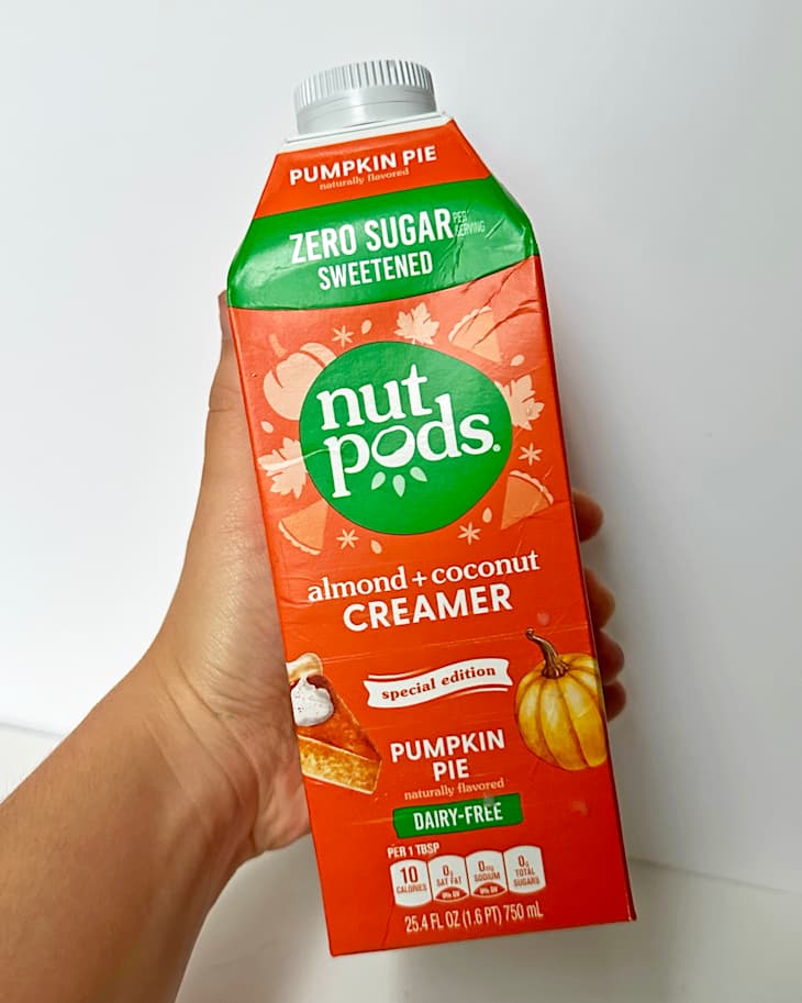 Pumpkin Pie flavored nut pods almond and coconut creamer carton held in hand, featuring autumn leaves and a pumpkin graphic.