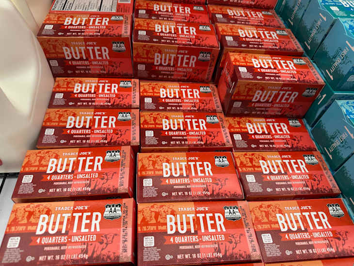 Rows of Trader Joe's unsalted butter boxes in red packaging, stacked in a grocery display.