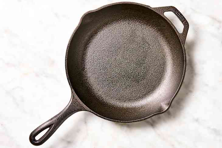 A beautifully seasoned and clean cast iron skillet on a marble surface