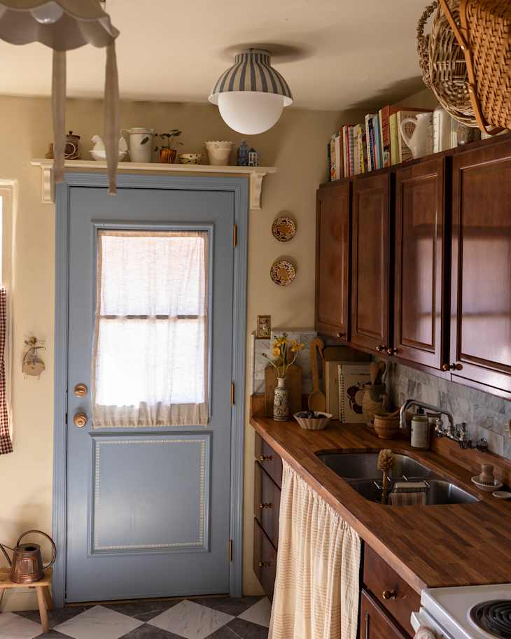 Blue painted door with linen curtains in newly renovated farmhouse inspired kitchen.