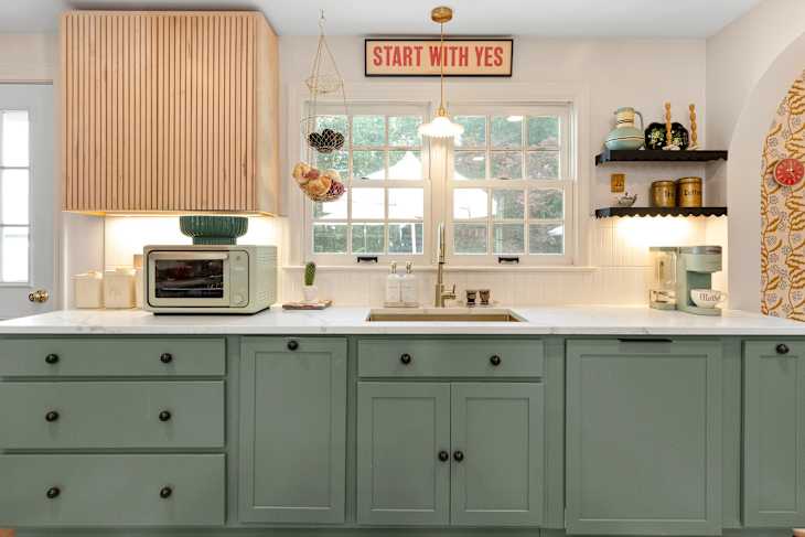 Kitchen with green cabinetry, large island, and checkerboard floor after renovation.