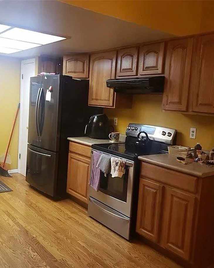 Kitchen with yellow walls, wooden cabinets, stainless steel stove, and black refrigerator, featuring a countertop and various kitchen items.