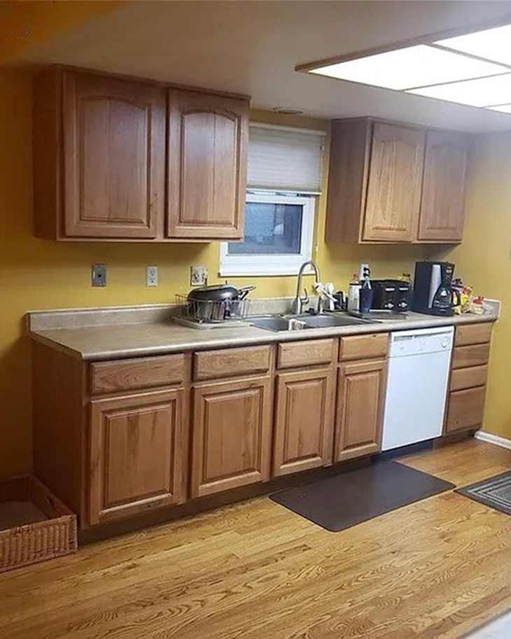 Kitchen with wooden cabinets, a sink, dishwasher, and countertop, featuring a window and yellow walls.