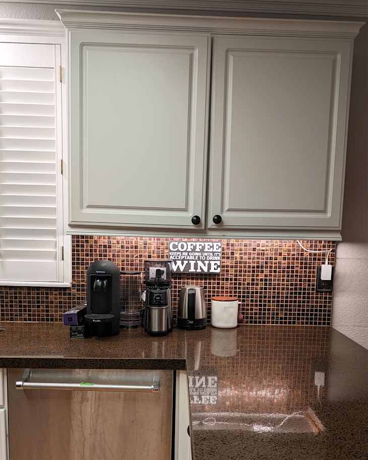 Dark knobs on light colored countertops in kitchen before renovation.