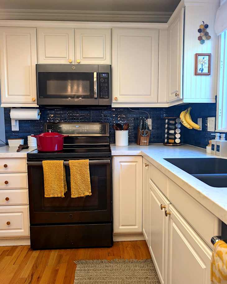 Red cookware on stovetop in newly renovated kitchen with white countertops.