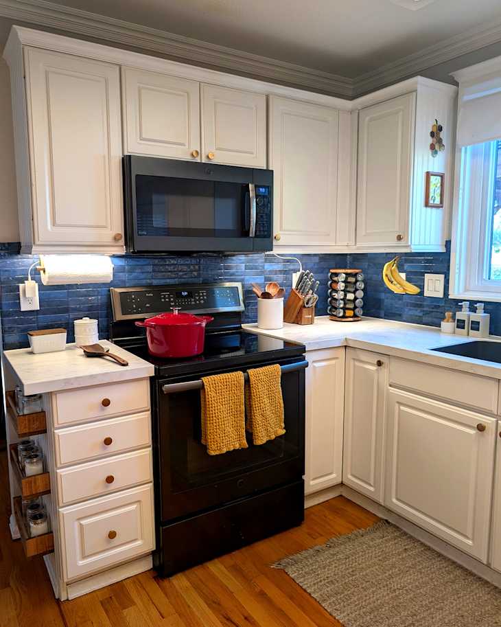 Banana hanging on hook in newly renovated kitchen with white countertops.