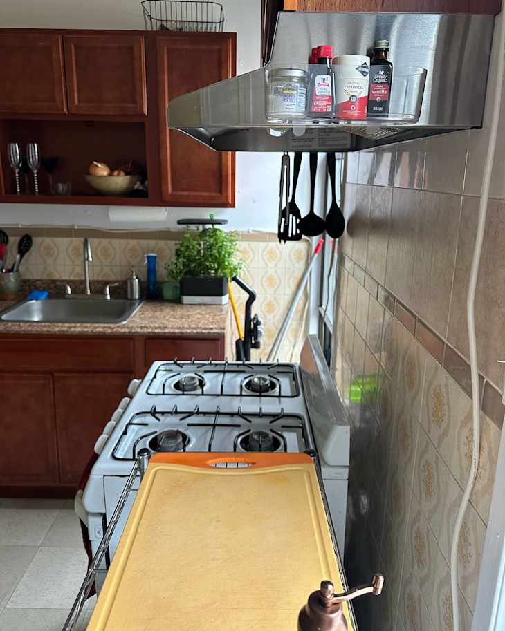 Spices stored in clear caddy side of stove exhaust.