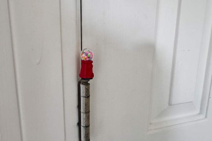 Miniature gumball machine on as a door hinge topper.