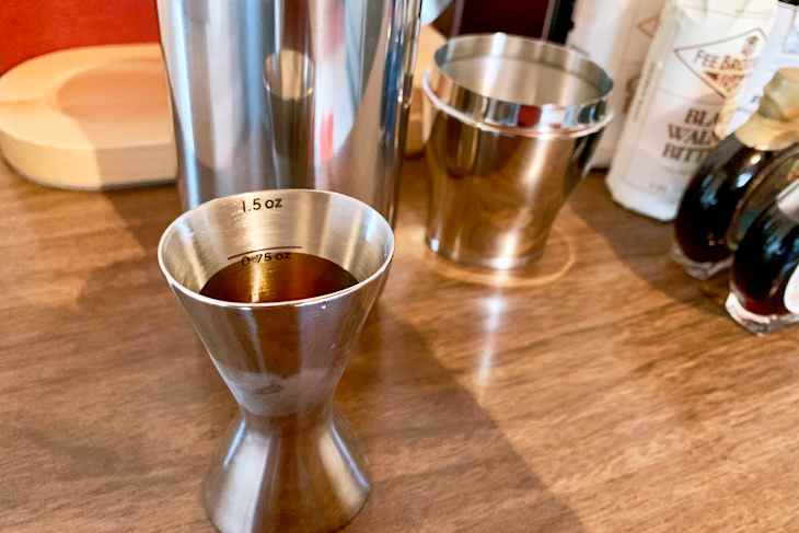 stainless steel jigger measuring 1.5 oz filled with liquid,