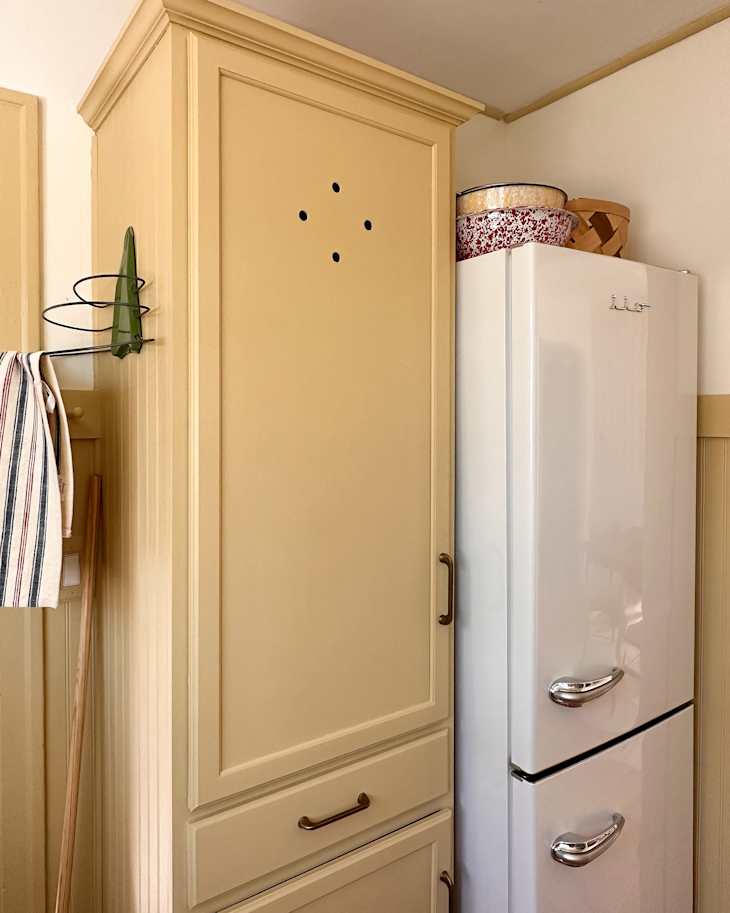Vintage inspired refrigerator in newly renovated kitchen with yellow cabinet beside.