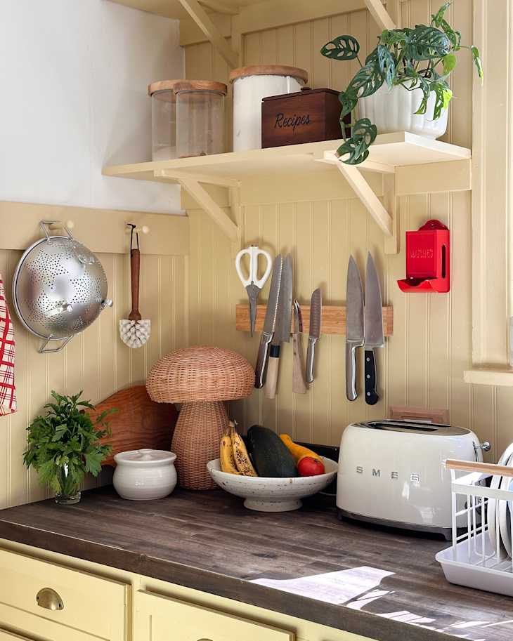 Knifes on magnetic strip in newly renovated kitchen with yellow wainscoting backdrop.