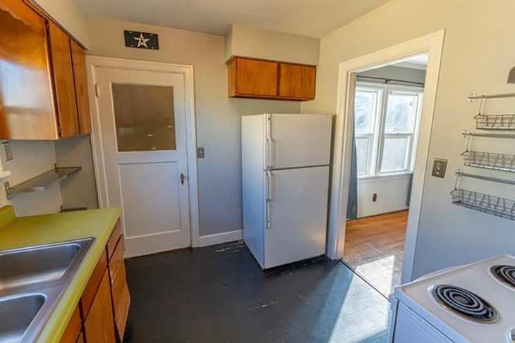 White refrigerator in kitchen before renovation.