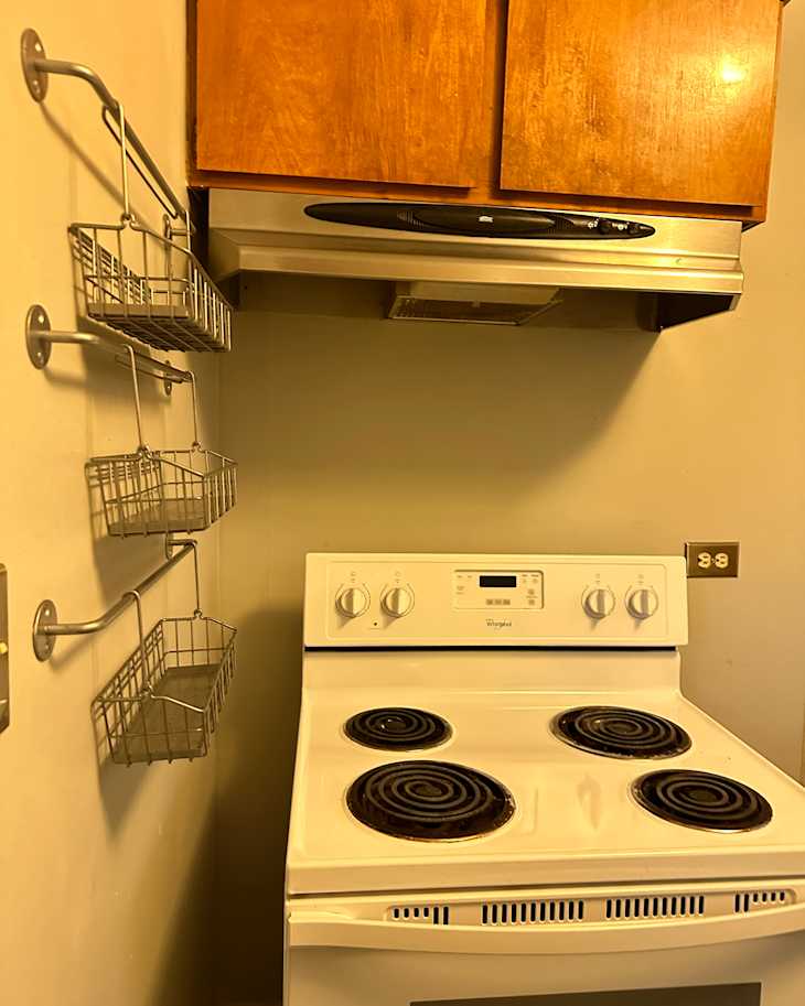 Dated electric stove with coils in vintage kitchen before renovation.