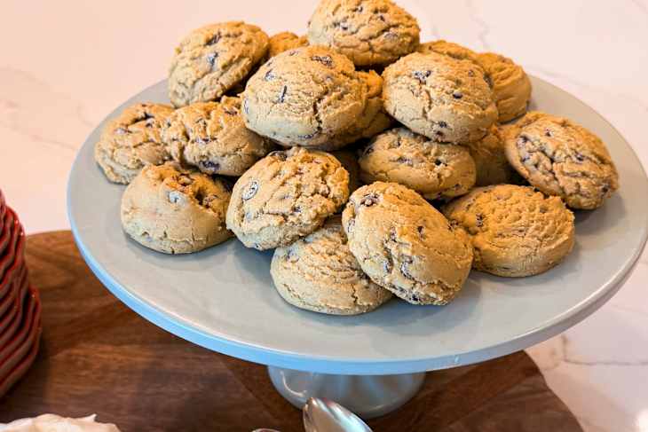 Plate of freshly baked cookies with chocolate chips, stacked high on a light blue cake stand.