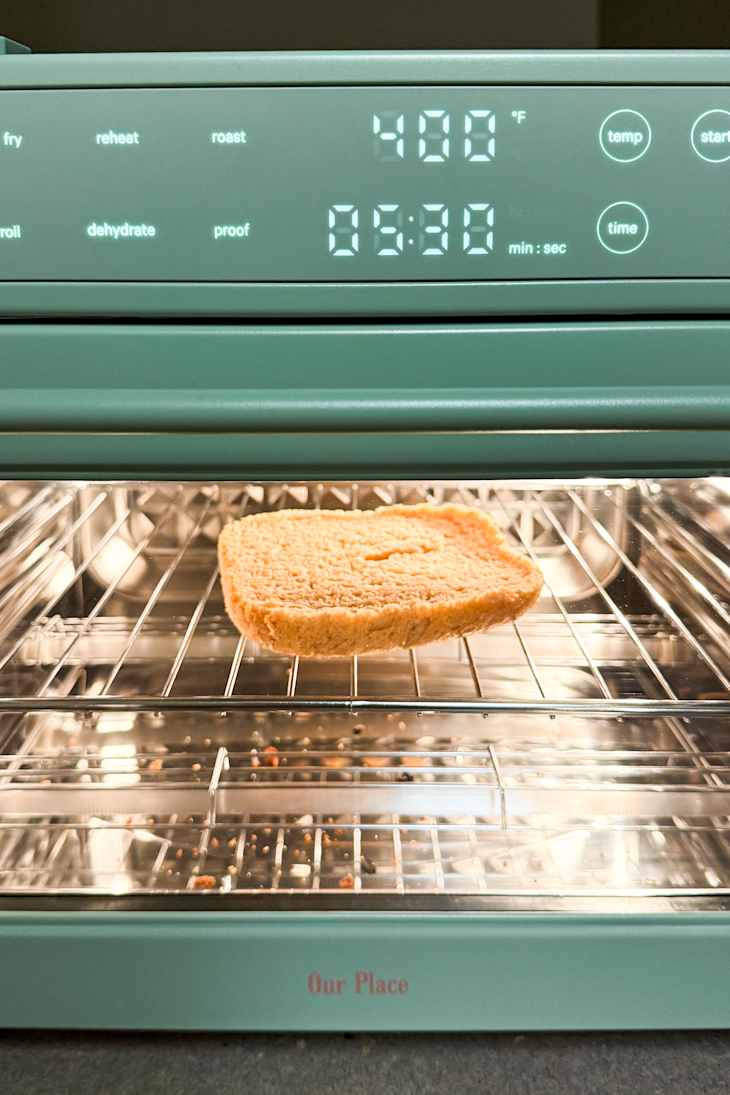 Toasted bread slice in a teal countertop air fryer oven displaying 400°F and 5:30 timer.