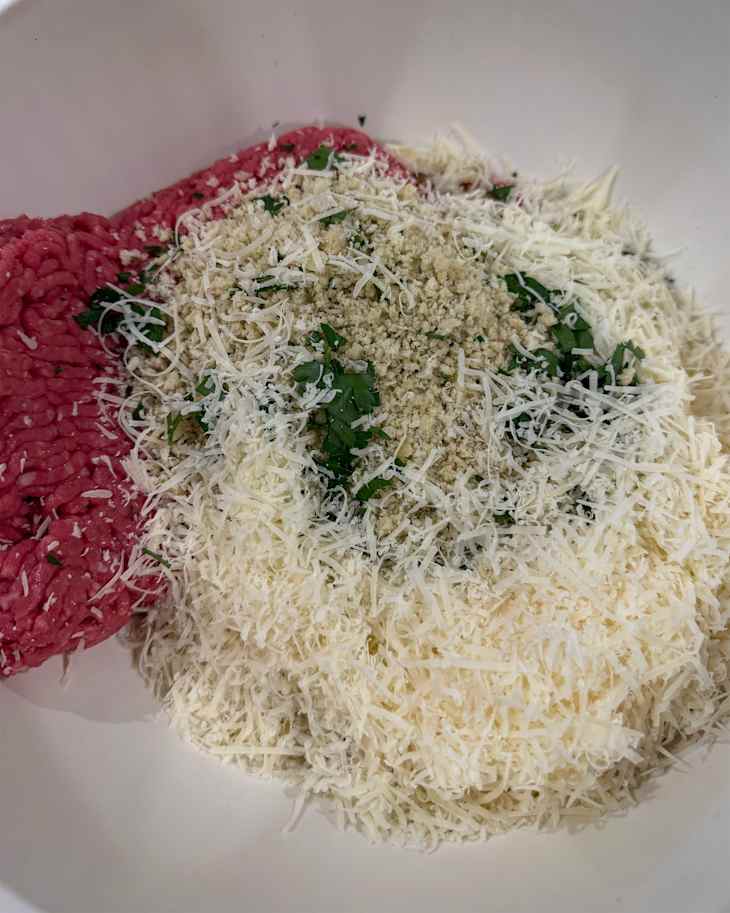 Breadcrumbs in bowl with other ingredients to make meatballs.