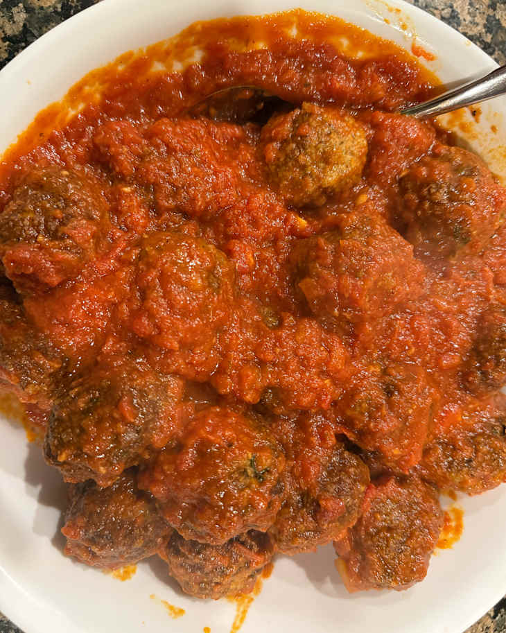 A bowl of tomato sauce covered meatballs.