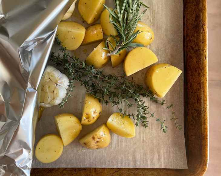 Potatoes and garlic on sheet pan before roasting.
