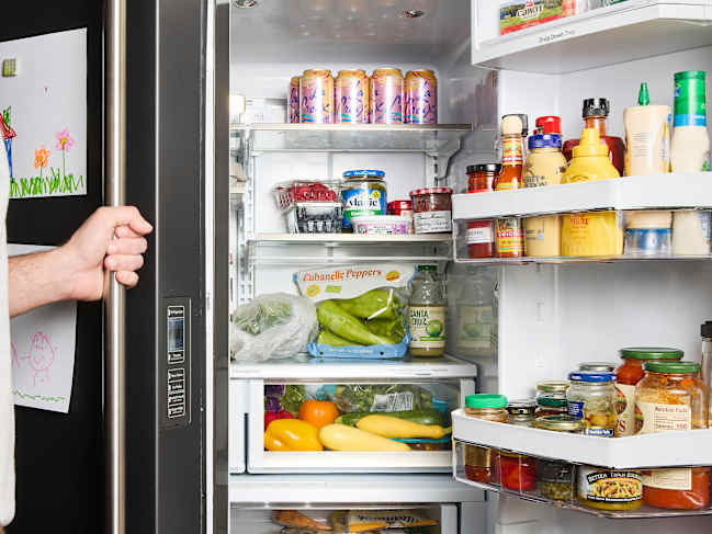 Refrigerator filled with various foods including fruits, vegetables, yogurt, drinks, and condiments.