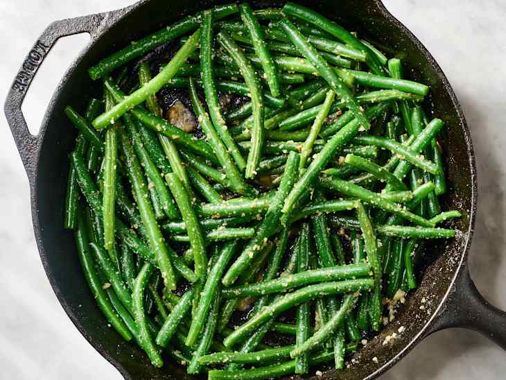 Sautéed green beans with garlic and seasoning in a cast iron skillet.