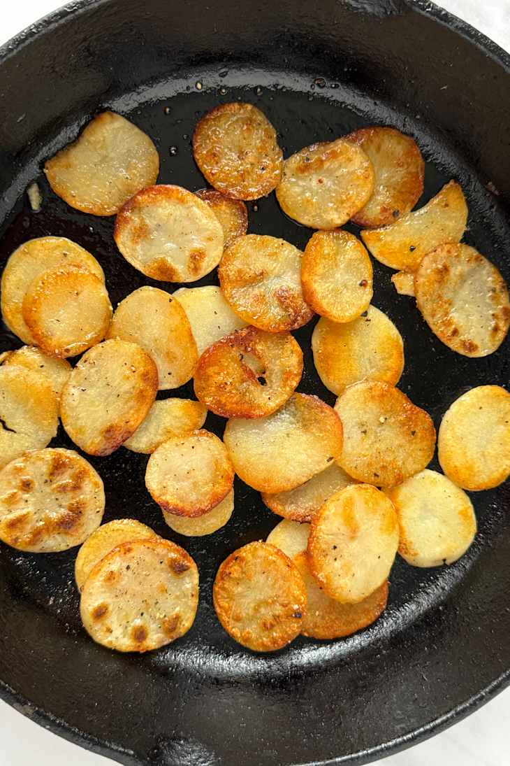 Crispy golden-brown potato chips scattered in a cast iron skillet.