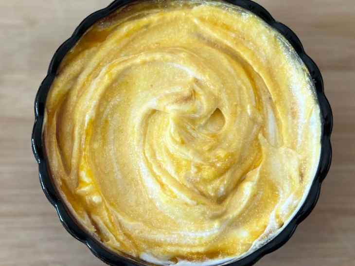 Pumpkin puree stirred into bowl of yogurt.
