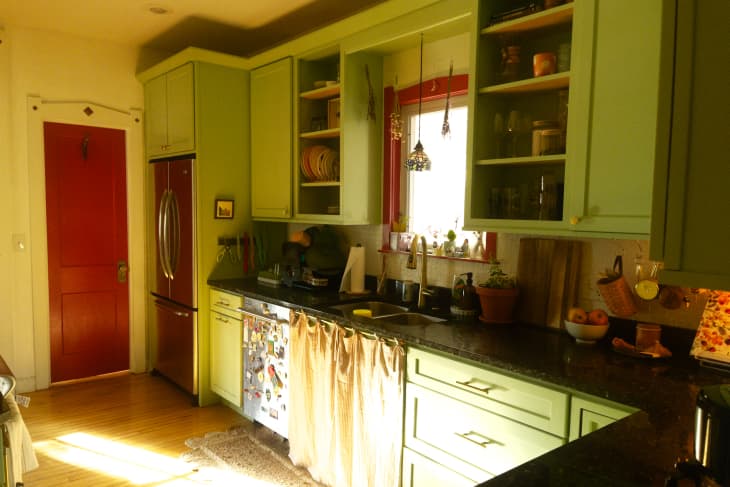 Red painted door and window frame in green painted kitchen.
