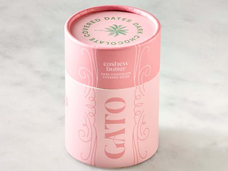 Container of dark chocolate-covered dates with a pink design, labeled "CATO" and "cashew butter."