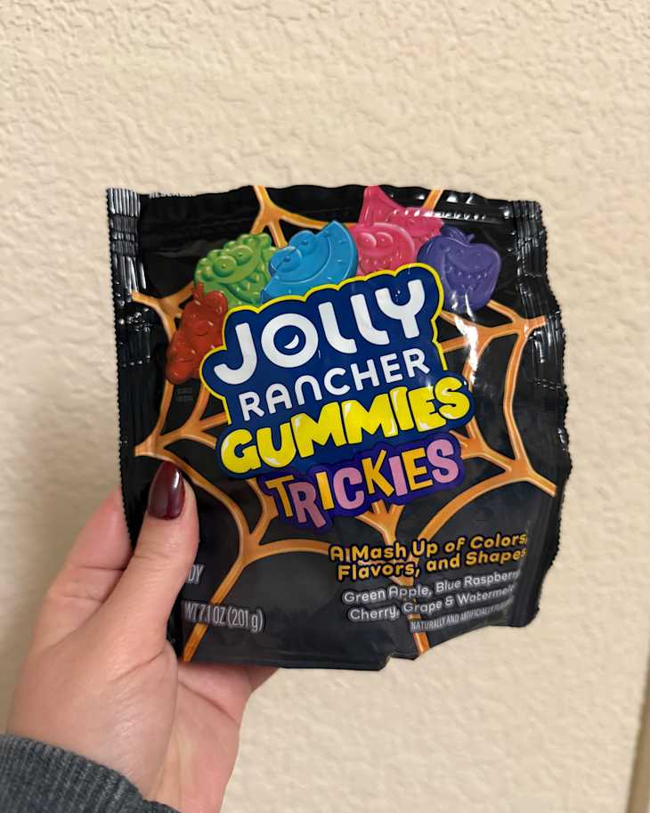 Someone holding a bag of Jolly Ranchers Trickies.
