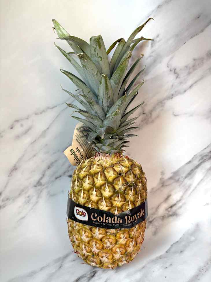Whole Colada Royale pineapple on countertop.