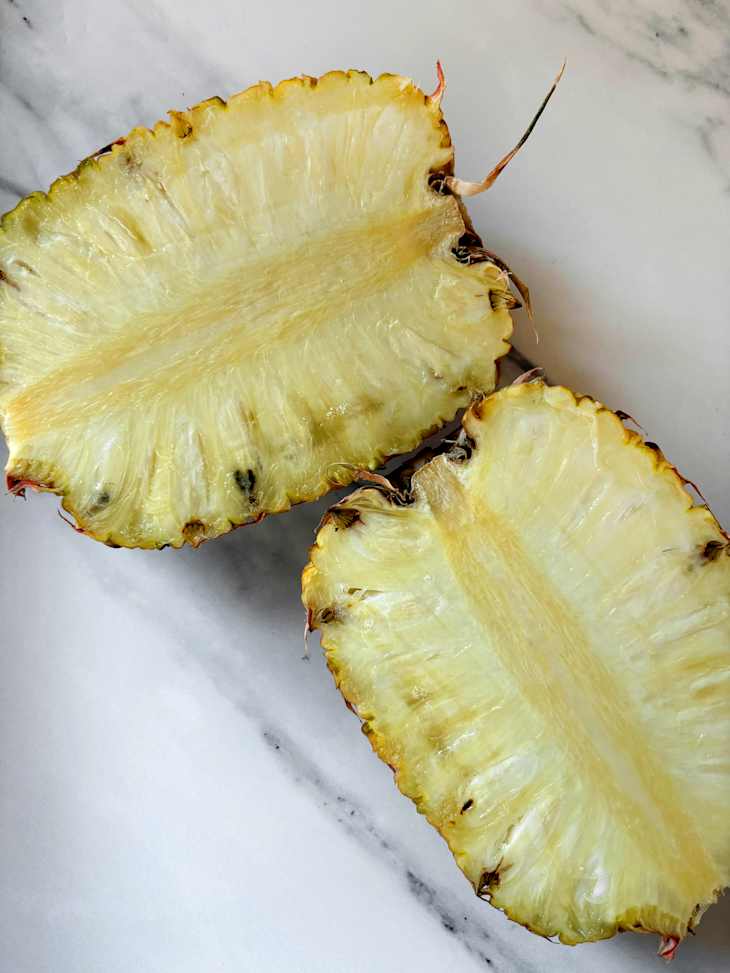 Halved Royle Colada pineapple on countertop.