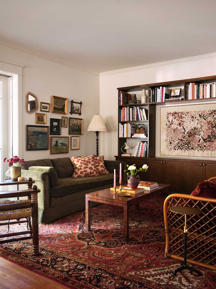 Cozy living room with a green sofa, patterned pillows, wooden coffee table, and a vibrant area rug, featuring framed art on the walls.