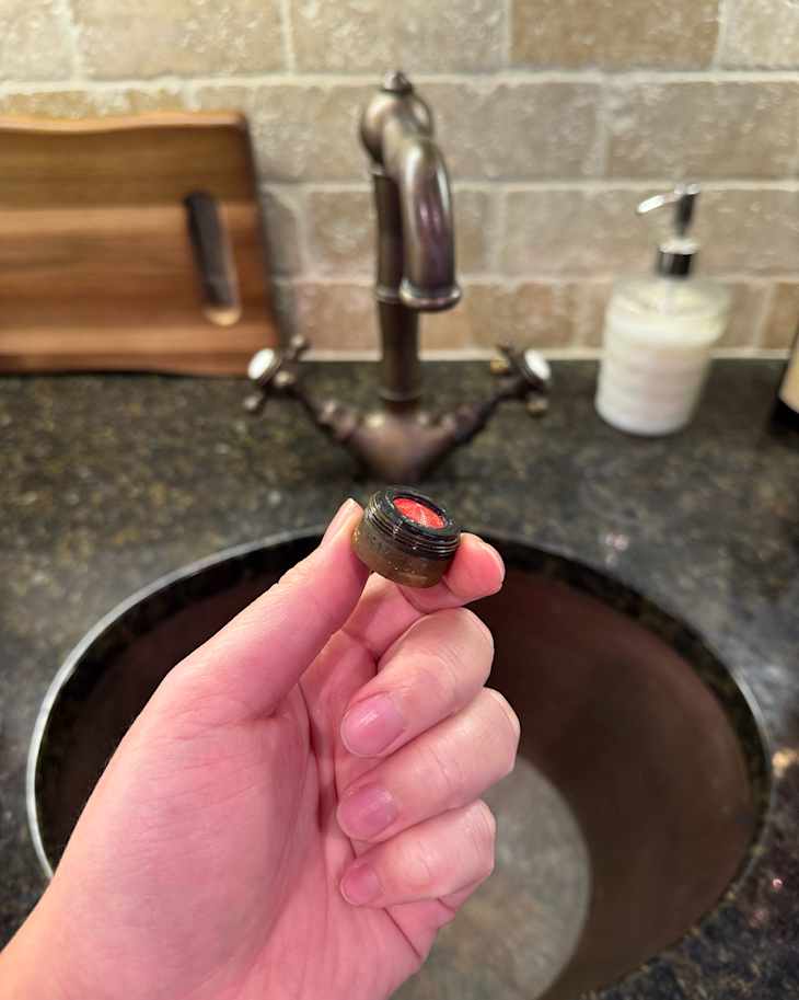 Someone holding a sink aerator.