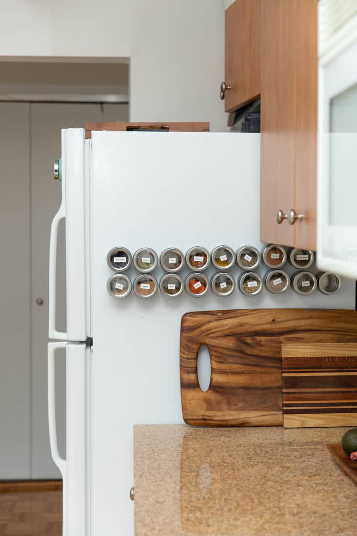 Kitchen with white fridge, magnetic spice jars, wooden cutting boards, and brown cabinets.