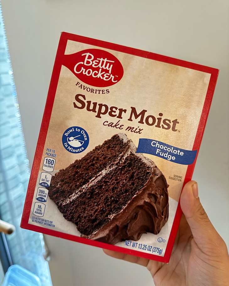 Someone holding box of Betty Crocker chocolate cake mix.