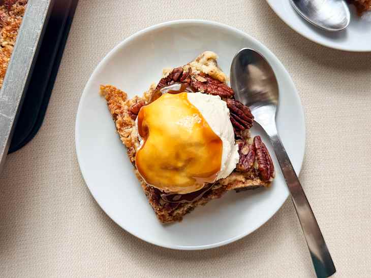 Serving of Pecan Pie Dump Cake on a plate with ice cream