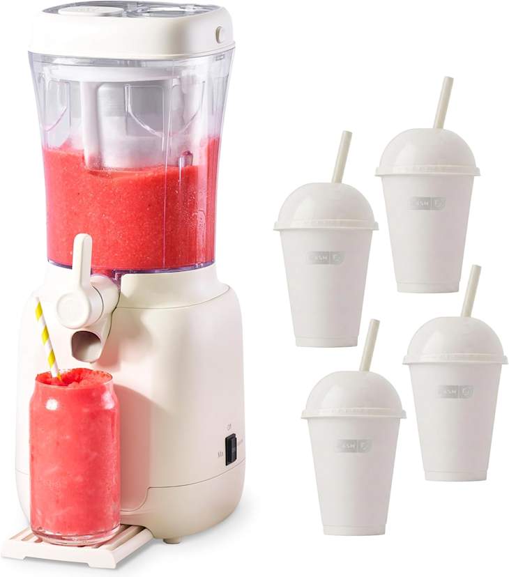 Slushie maker with a pink slush in a glass jar and four white cups with straws beside it.