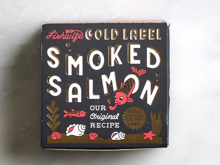 Black packaging for Fishwise Gold Label Smoked Salmon featuring bold white text, fish illustrations, and decorative elements.