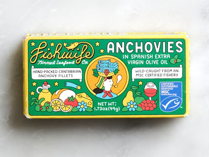 Colorful packaging for Fishwife canned anchovies, featuring illustrations of food items and a character, with details on sustainability.