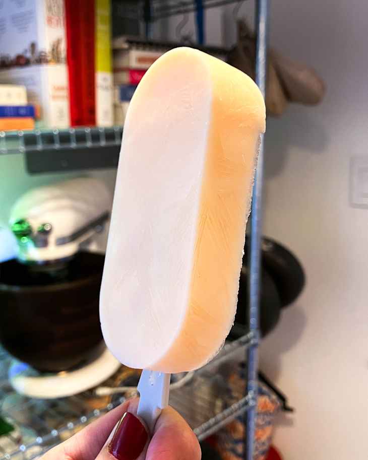 Someone holding kefir popsicle.