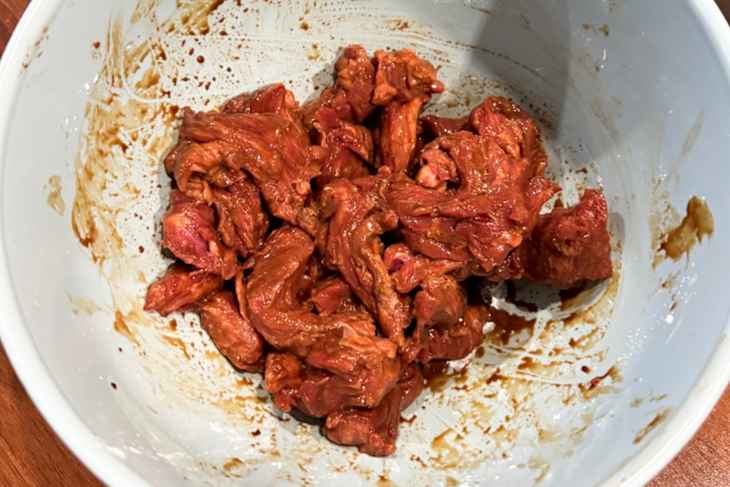 Marinated strips of meat in a bowl .