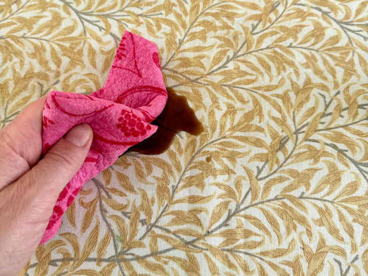 someone cleaning their oilcloth tablecloth with a rag