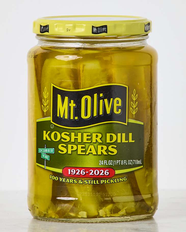 Jar of Mt. Olive Kosher Dill Spears pickles, featuring a yellow lid and green label with text and graphics.